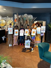 a group of people holding up paintings in a lobby