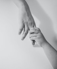 a black and white photo of a hand holding a child's hand