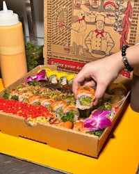 a person is putting sushi into a box
