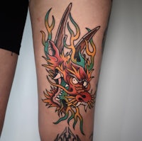 a tattoo of a dragon on a woman's thigh