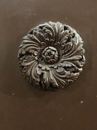 an ornate metal flower on a brown door