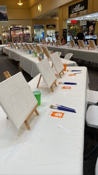 a table with easels and paints in a shopping mall