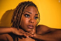 a woman with dreadlocks posing on a yellow background