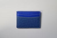 a blue leather card holder on a white surface