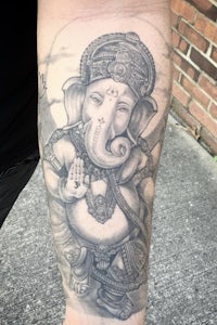 a tattoo of a ganesha on a man's forearm
