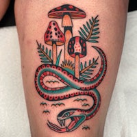 a tattoo of a snake and mushrooms on the thigh