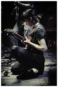 a woman crouching down while playing an electric guitar