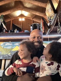 a man and his two children in a wooden cabin