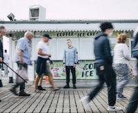 a group of people walking on a boardwalk near an ice cream shop
