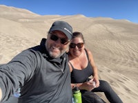 a man and woman taking a selfie in a sand dune