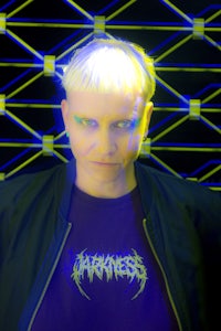 a woman with blonde hair standing in front of a neon wall