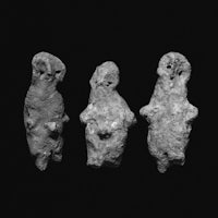 three stone figurines on a black background