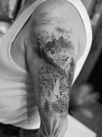 a black and white image of a man with a mountain tattoo