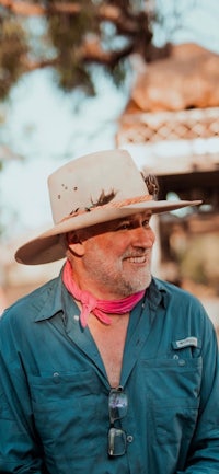 a man wearing a cowboy hat and pink scarf