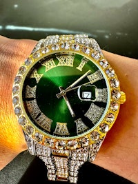 a woman's wrist with a green and gold watch