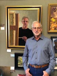 a man standing in front of paintings in a gallery