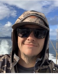 a man in a camouflage hat is taking a selfie on a boat