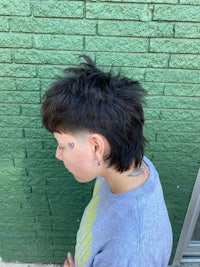 a woman with a shaved head in front of a brick wall