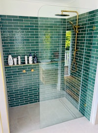 a green tiled bathroom with a glass shower stall