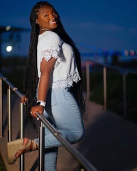 a young black woman leaning on a railing at night