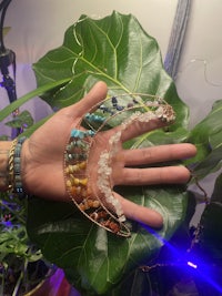 a hand holding a necklace with different colored gemstones