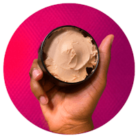 a hand holding a jar of cream with a pink background