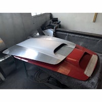 the hood of a red and white car is being worked on
