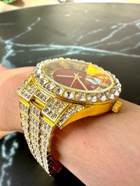 a person wearing a gold watch with diamonds on it