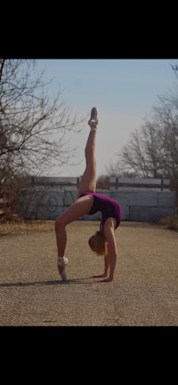 a girl doing a handstand on a road