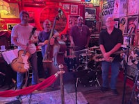 a group of musicians standing in front of a bar