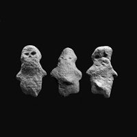 a group of three stone statues on a black background