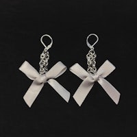 a pair of silver bow earrings on a black background