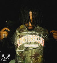 a man with dreadlocks wearing a camouflage shirt