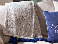 a blue and white throw with tassels on a couch