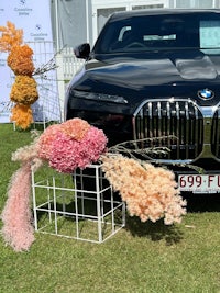 a bmw 7 series parked in front of a flower arrangement