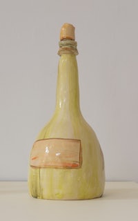 a yellow bottle with a wooden lid sitting on a table