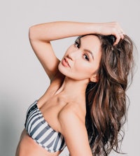 a young woman in a striped bikini posing on a gray background