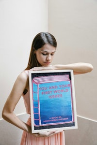a woman holding up a book that says you are your first work of art