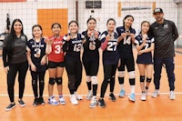 a group of girls posing for a picture on a volleyball court