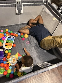 a man and a child laying down in a playpen