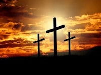 three crosses are silhouetted against a sunset