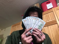 a man in a hoodie holding a bunch of money