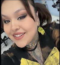 a woman with tattoos and earrings smiling at the camera