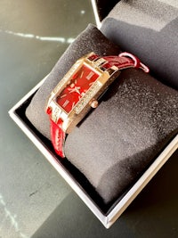 a red watch in a box sitting on a table