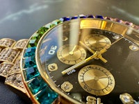 a gold watch with multi colored crystals on it