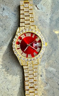 a gold and red watch with diamonds on it