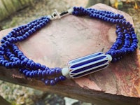 a blue and white beaded necklace on a rock