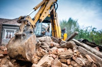 an excavator is removing rubble from a house