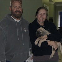 a man and woman holding a puppy in a hallway