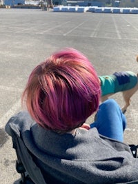 a person in a wheelchair with pink hair and a dog
